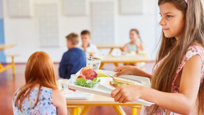 Une collégienne avec son plateau à la cantine